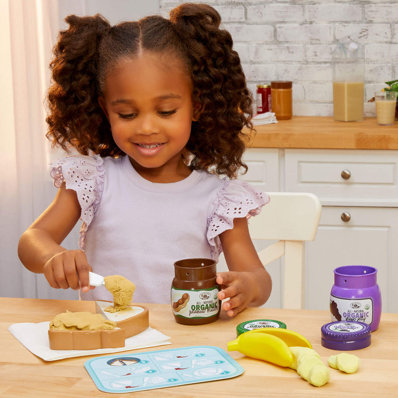 girl spreading play sand peanut butter